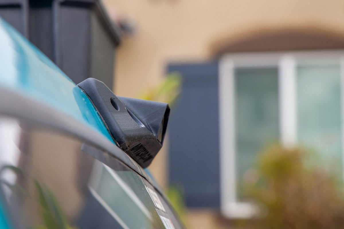Black plastic camera mount attached to a teal vehicle roof